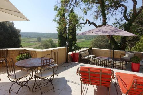 un patio avec une table, des chaises et un parasol dans l'établissement Le Grand Saint Paul, à Rognes