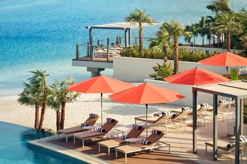 einen Pool mit Stühlen und Sonnenschirmen am Meer in der Unterkunft Grand Hyatt Abu Dhabi Hotel & Residences Emirates Pearl in Abu Dhabi