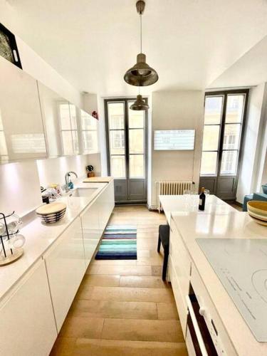 une grande cuisine avec des comptoirs blancs et des fenêtres dans l'établissement Beaux T2 et T3 climatisés dans le triangle d'or, à Bordeaux