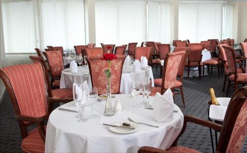 un comedor con mesas blancas y sillas rojas en Ox Hotel Carlisle en Carlisle