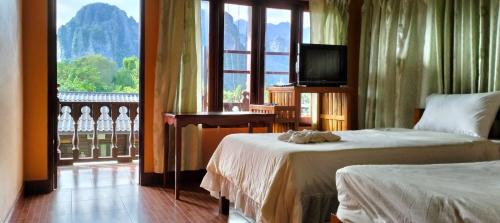 a hotel room with two beds and a television at Bungalows Le Jardin VANGVIENG in Vang Vieng