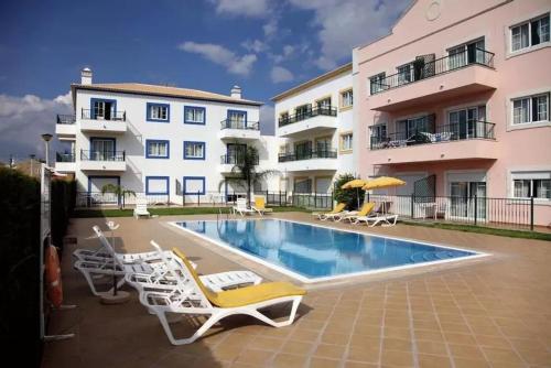 a swimming pool with lounge chairs and a building at Apartamento Altura T2 in Altura