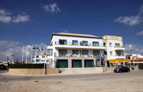 a white building with a car parked in front of it at Apartamento Altura T2 in Altura