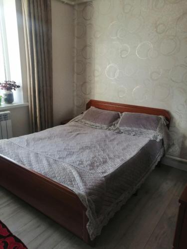 Schlafzimmer mit einem großen Bett mit einem Kopfteil aus Holz in der Unterkunft Гостевой дом (Hostel) in Kochkorka
