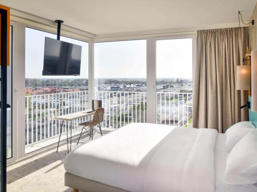 sypialnia z łóżkiem oraz balkon z telewizorem w obiekcie ibis Styles Bredene w mieście Bredene