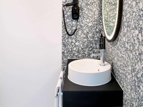 a bathroom with a white sink and a mirror at ibis Styles Bredene in Bredene