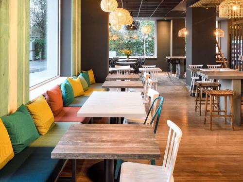 un restaurante con mesas de madera y sillas coloridas en ibis Styles Bredene, en Bredene