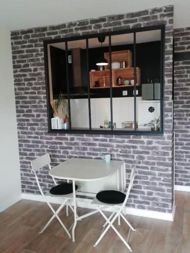 une table blanche et deux chaises contre un mur de briques dans l'établissement Studio agréable dans résidence, à Joué-lès-Tours