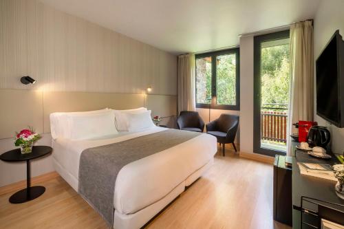 une chambre d'hôtel avec un lit et une télévision dans l'établissement NH Collection Andorra Palomé, à La Massana