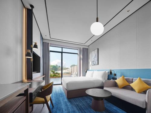 a hotel room with a bed and a couch at Hilton Garden Inn Huizhou North Railway Station in Huizhou