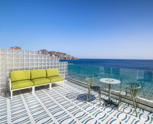 Barceló Benidorm Beach - Adults Recommended في بنيدورم: شرفة مع أريكة وطاولة والمحيط