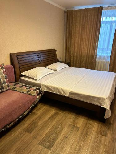 een slaapkamer met een groot bed en een bank bij Сеть BRAUN Сатпаева 11 in Pavlodar