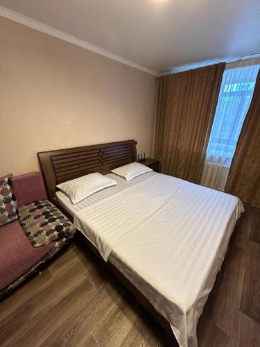 een slaapkamer met een groot wit bed en een raam bij Сеть BRAUN Сатпаева 11 in Pavlodar