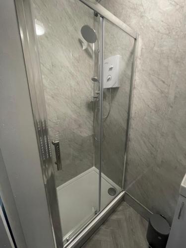 a shower with a glass door in a bathroom at Bellshill , Belvidere central upper apartment in Bellshill