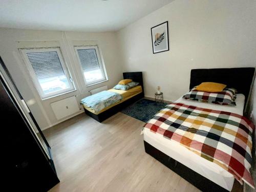 a bedroom with two beds and two windows at Relax Wohnung Bickenbach in Bickenbach
