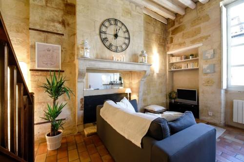 un salon avec un canapé et une horloge au mur dans l'établissement T1 Bis au coeur du vieux Bordeaux, à Bordeaux