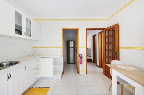 a kitchen with white cabinets and a refrigerator at Gilove House in Póvoa de Varzim