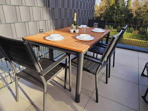 een houten tafel met stoelen en een fles wijn bij Apartment mit Jacuzzi Enschede 10km in Gronau