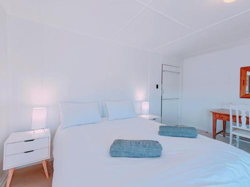 una camera da letto con un letto bianco con due cuscini sopra di Timber's Ocean House a Simonʼs Town