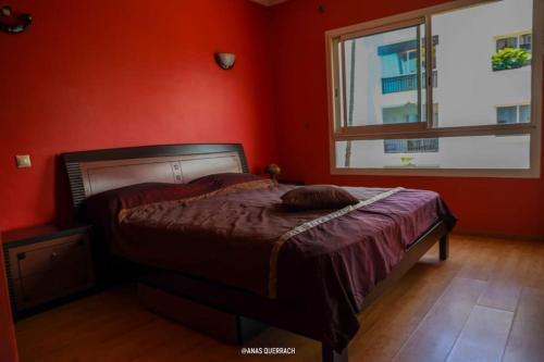 a red bedroom with a bed and a window at Appartement vue piscine à marina in Agadir