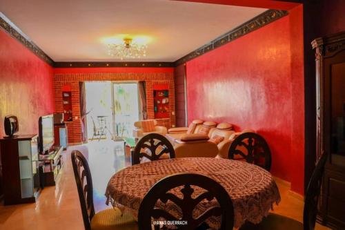 a dining room with red walls and a table and chairs at Appartement vue piscine à marina in Agadir