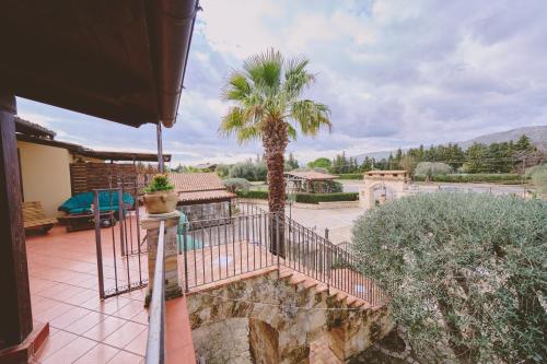 a patio with a palm tree and a fence at B&B Casale degli Ulivi in Avola