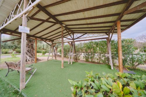 a wooden pavilion with a bench in a garden at B&B Casale degli Ulivi in Avola