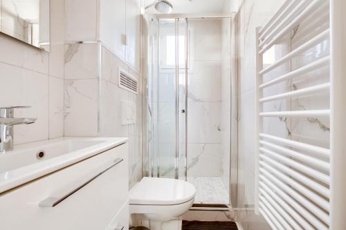 a white bathroom with a toilet and a shower at Volontaire in Paris