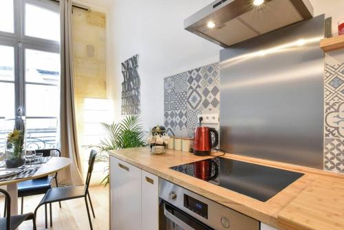 une cuisine avec un réfrigérateur en acier inoxydable et une table dans l'établissement Grand 2 pièces entre vieux Bordeaux et quais !, à Bordeaux