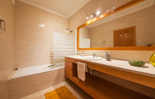 a bathroom with a sink and a mirror and a tub at Alto do Quintao Apartments in Portimão