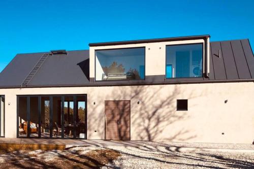 una casa con techo negro y ventanas en Luxurious design villa near beach - sleeps 8+, en Klintehamn