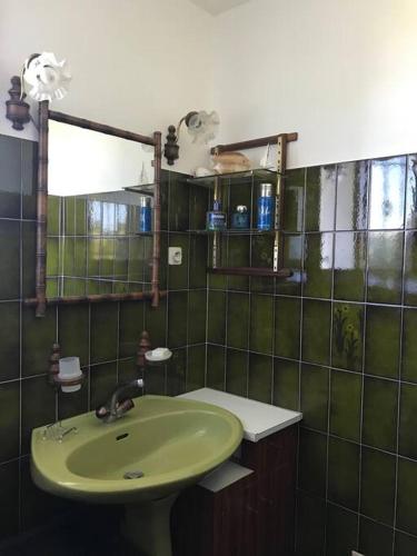 La salle de bains verte est pourvue d'un lavabo et d'un miroir. dans l'établissement Comme chez Mamie, maison entière 1-6 personnes, à Alby-sur-Chéran
