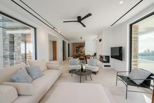 a living room with a white couch and a ceiling fan at Elia Cove Luxury Villa with private Pool in Loutraki