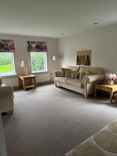 a living room with a couch and two windows at Riverview Cottage in Gortnessy Upper