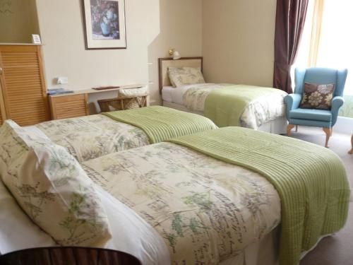 a room with three beds and a blue chair at Melbourne Guest House in Rhyl