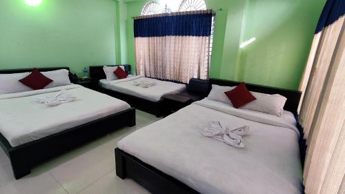 three beds in a room with green walls at Grand Selim Resort & Tour – GSRT in Sreemangal