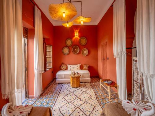 a living room with orange walls and a bed at Riad Maialou & SPA in Marrakech