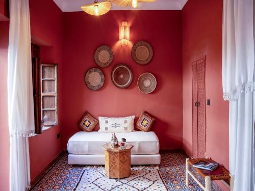 a bedroom with red walls with a bed and a table at Riad Maialou & SPA in Marrakech