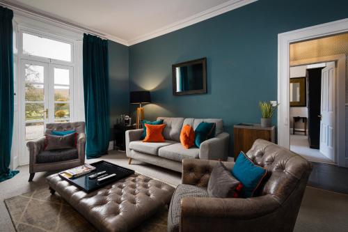 un soggiorno con pareti blu e divano in pelle di The Old Manse of Blair, Boutique Hotel & Restaurant a Blair Atholl
