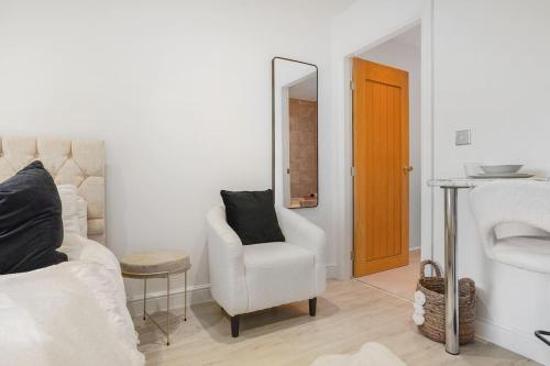 een woonkamer met een witte stoel en een spiegel bij Little Laxford in Fazeley