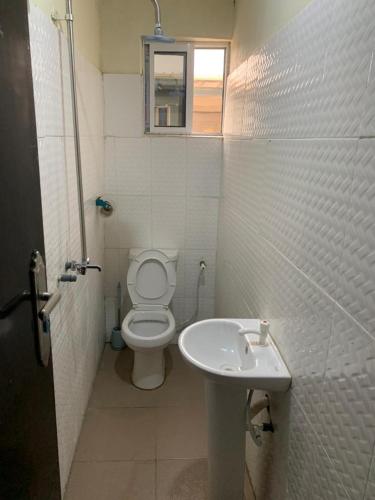 een witte badkamer met een toilet en een wastafel bij TSG Hotel in Ado Ekiti