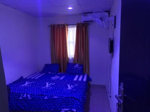 sypialnia z łóżkiem z niebieską pościelą i oknem w obiekcie TSG Hotel w mieście Ado Ekiti