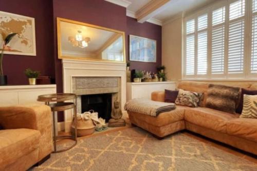 a living room with a couch and a fireplace at Luxury 4 Bed 2 Bath House with Garden near Wimbledon in London
