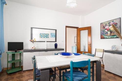 a dining room with a white table and blue chairs at Casa Vacanza Gungui in Capo Comino