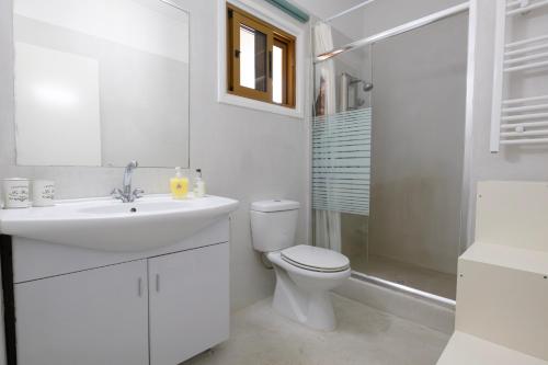 een witte badkamer met een toilet en een wastafel bij Captivating 2-Bed House in Alaminos