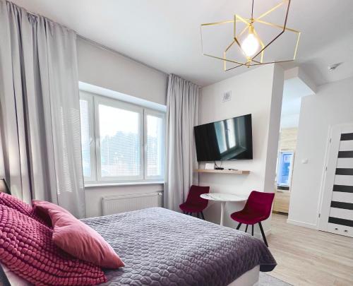 a bedroom with a bed with red chairs and a tv at Apartamenty Pokoje Willa Bielany in Warsaw