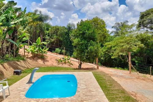 une piscine bleue dans une cour arborée dans l'établissement Chácara prox Rota do Vinho com piscina, churrasqueira, área verde, animaizinhos e muito sossego, à São Roque