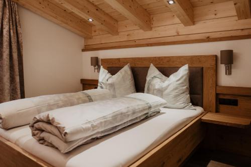 um quarto com uma cama com lençóis brancos e almofadas em Bergler Hoamat - Mountain Hideaway em Navis