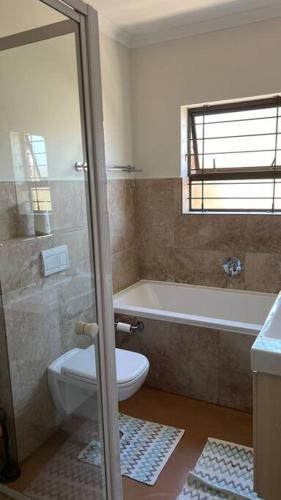 a bathroom with a toilet and a tub and a sink at Bosch Villa in Cape Town