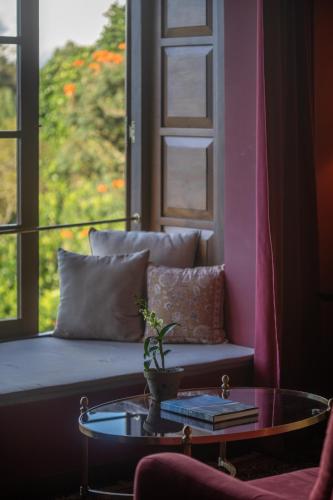 a living room with a couch and a table and a window at Kandy Dendrobium House in Kandy